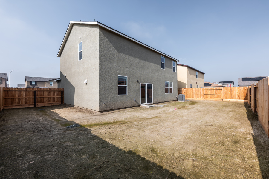 A grey house with a fence around it.