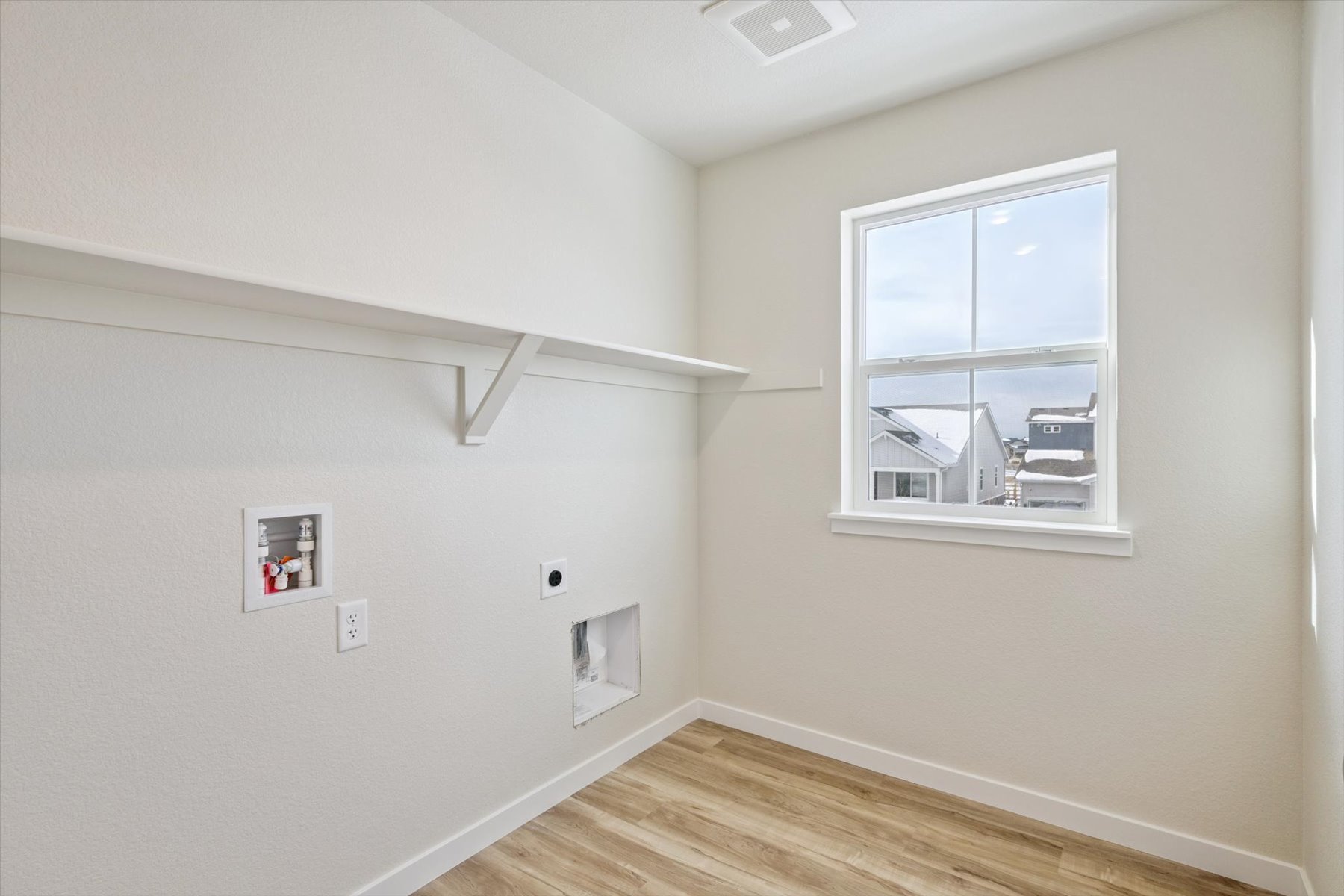 A room with a window and a wood floor.