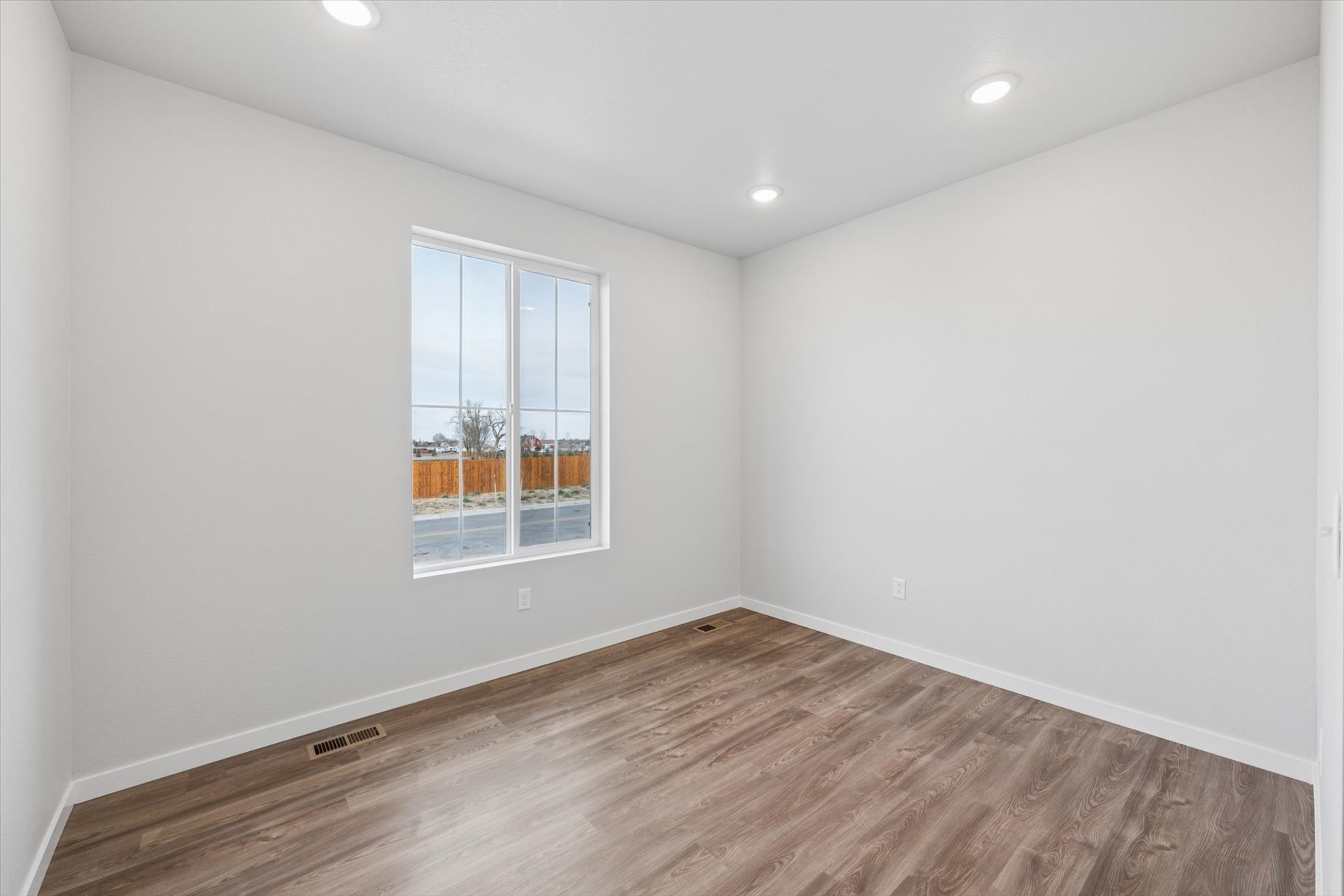A room with a wood floor and a window with a wood floor.