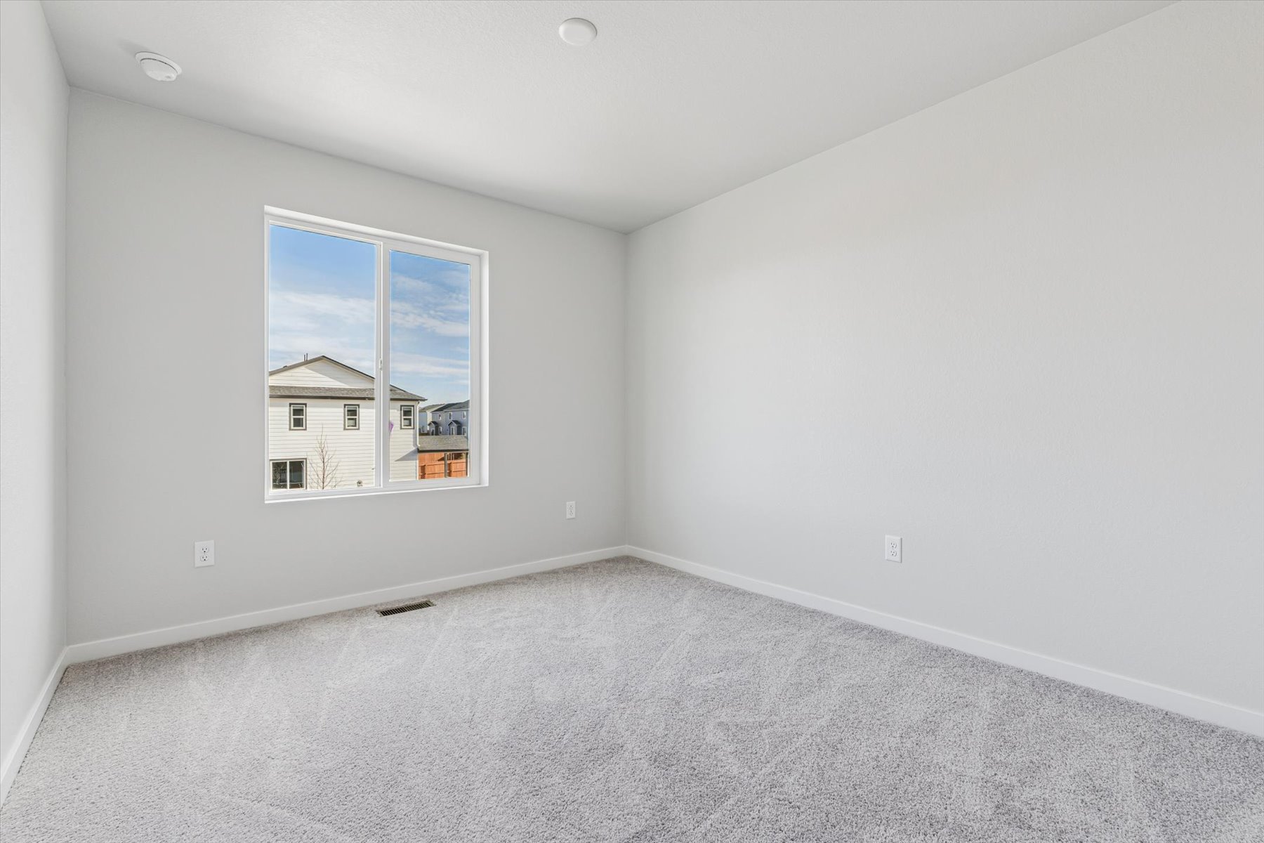 A room with a window and a white wall.