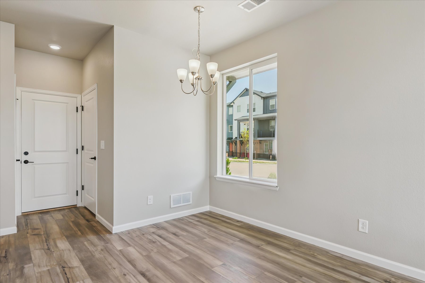 A room with a wood floor and a window with a light on.