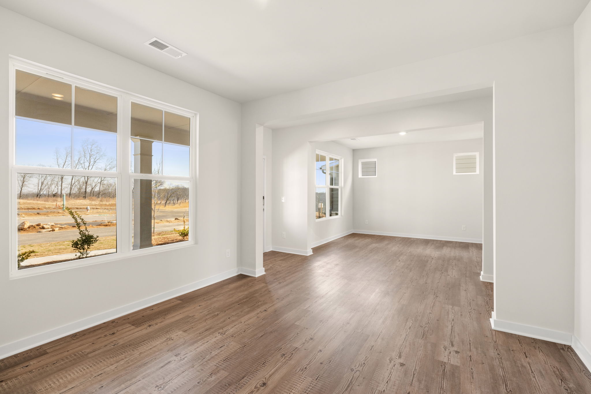 A room with a wood floor and a window with a view of the outside.