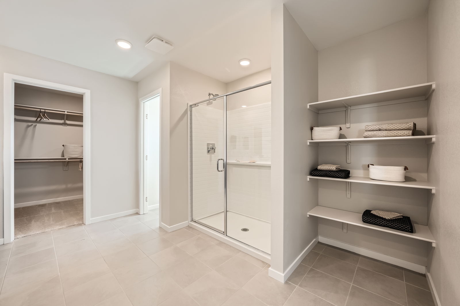 A room with a glass door and white shelves.