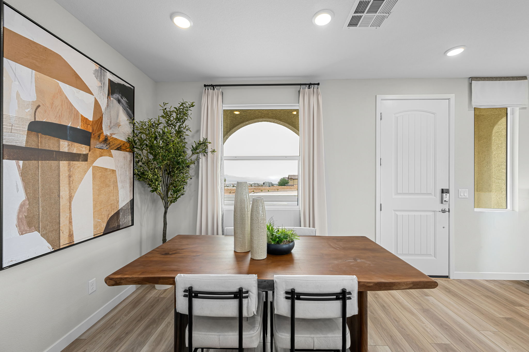 A dining room table with chairs and a painting on the wall.
