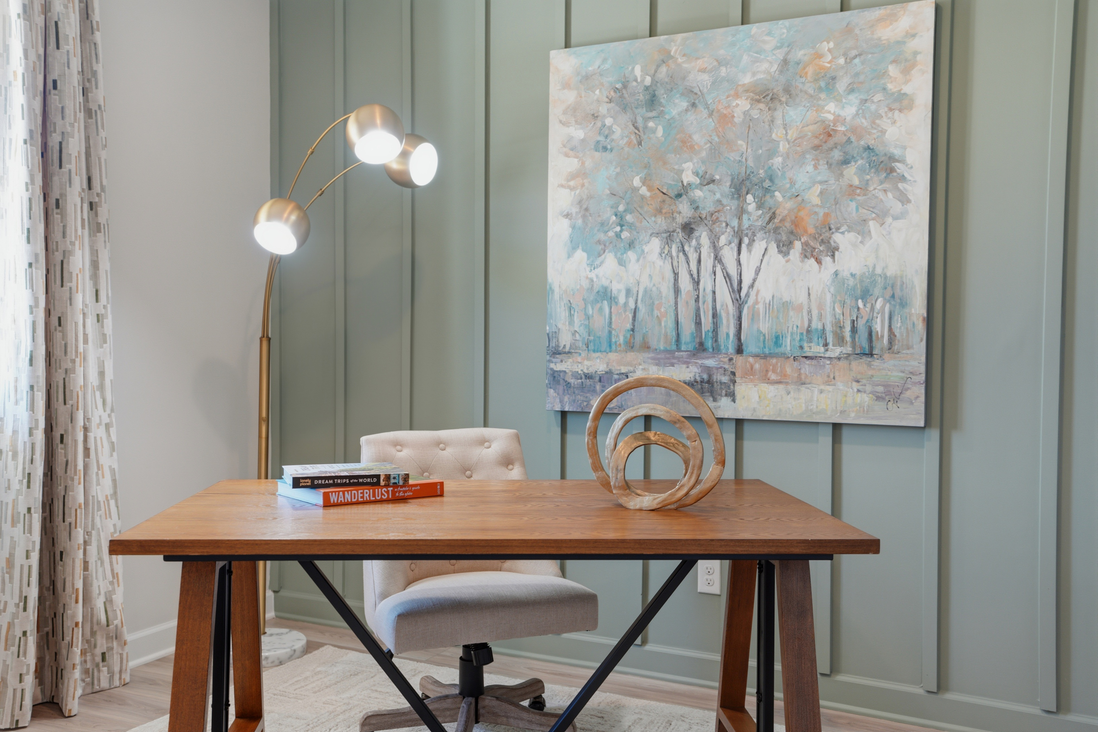 A table with a lamp and a painting on the wall.