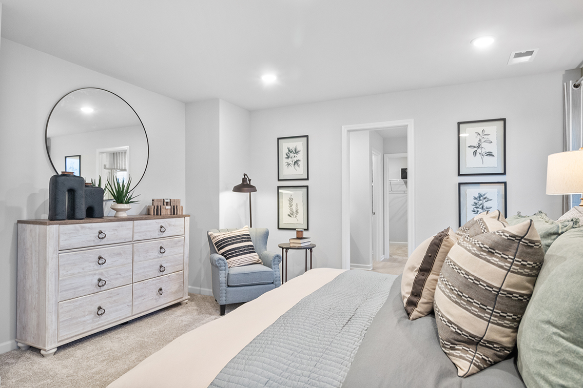 A bedroom with a bed and a chair.