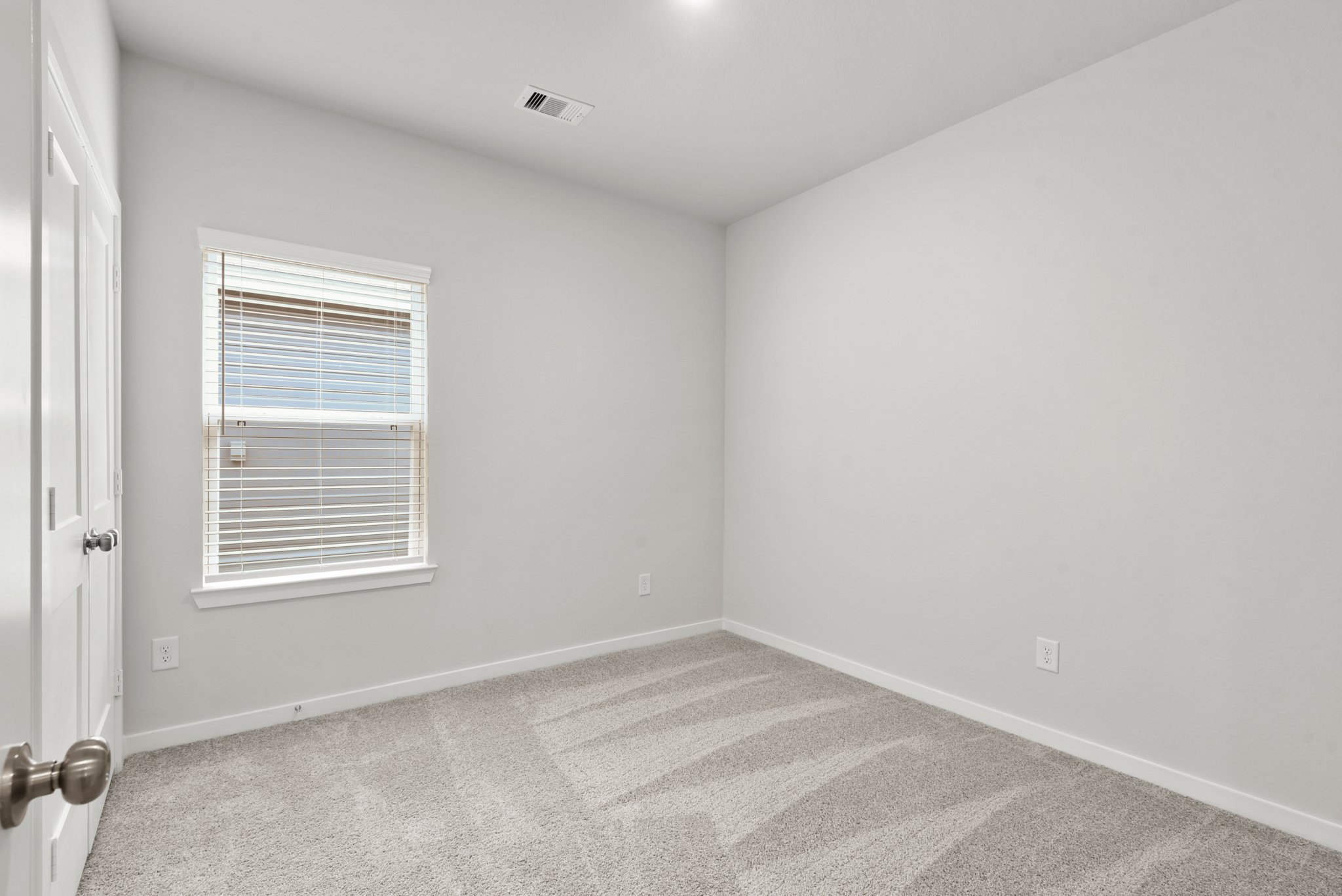 A room with a carpet and a window.