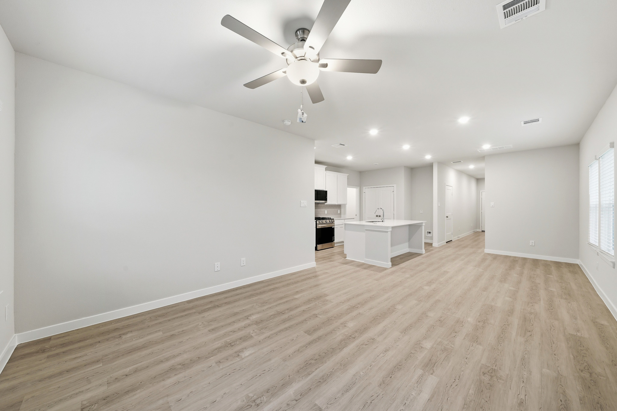 A large empty room with a ceiling fan and a wood floor.