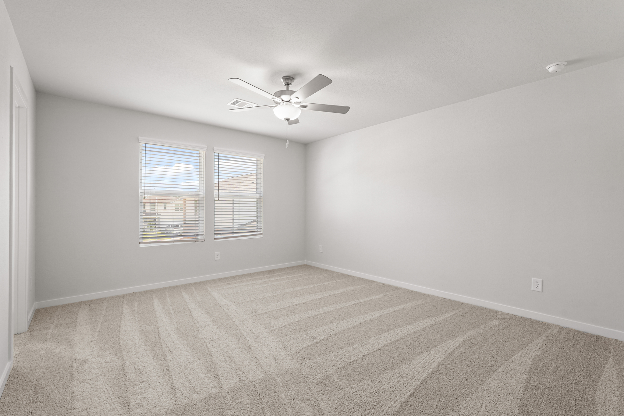 A room with a ceiling fan and a carpet.