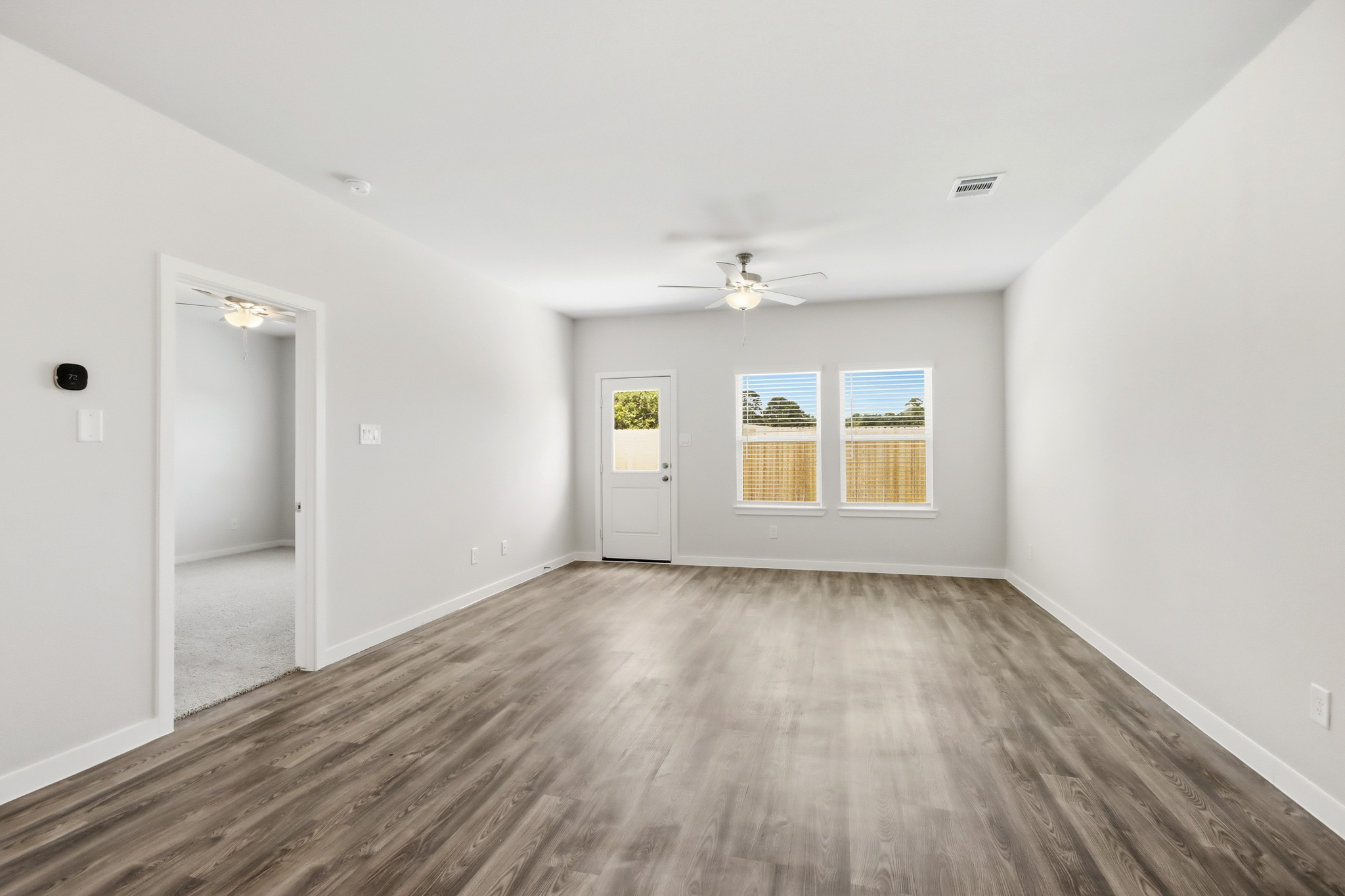 A room with a wood floor and a wood floor with a ceiling fan.