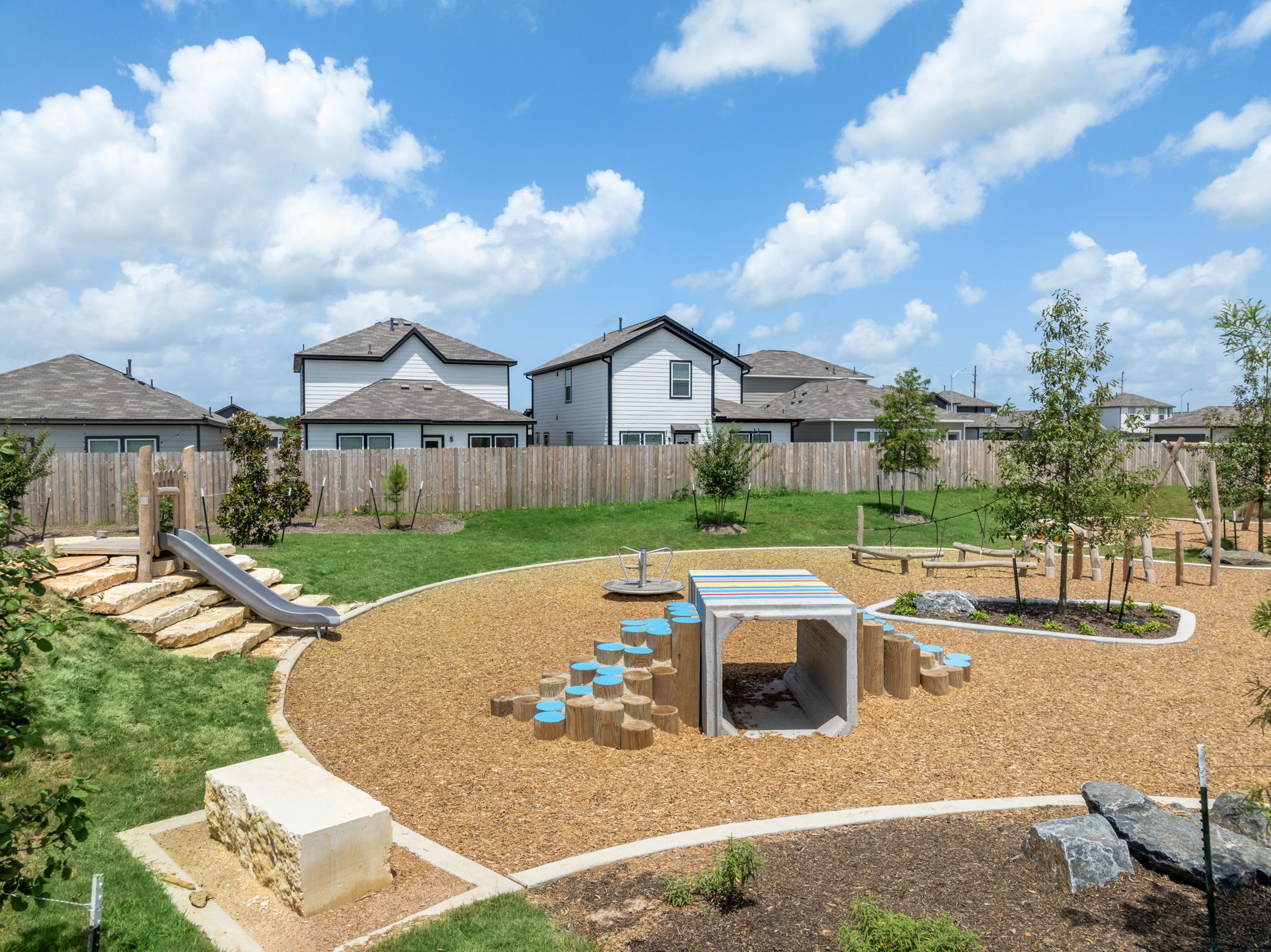 A backyard with a fence and a yard with a house in the background.
