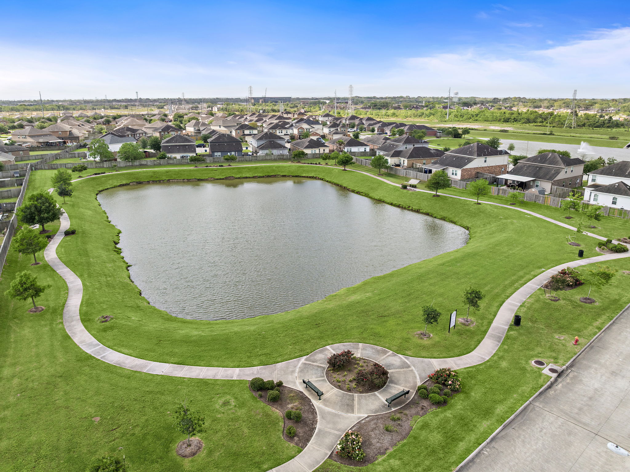 A pond surrounded by grass and buildings.