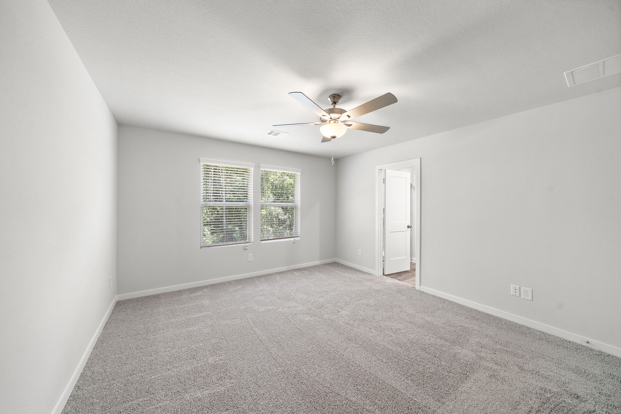 A room with a ceiling fan and a door.