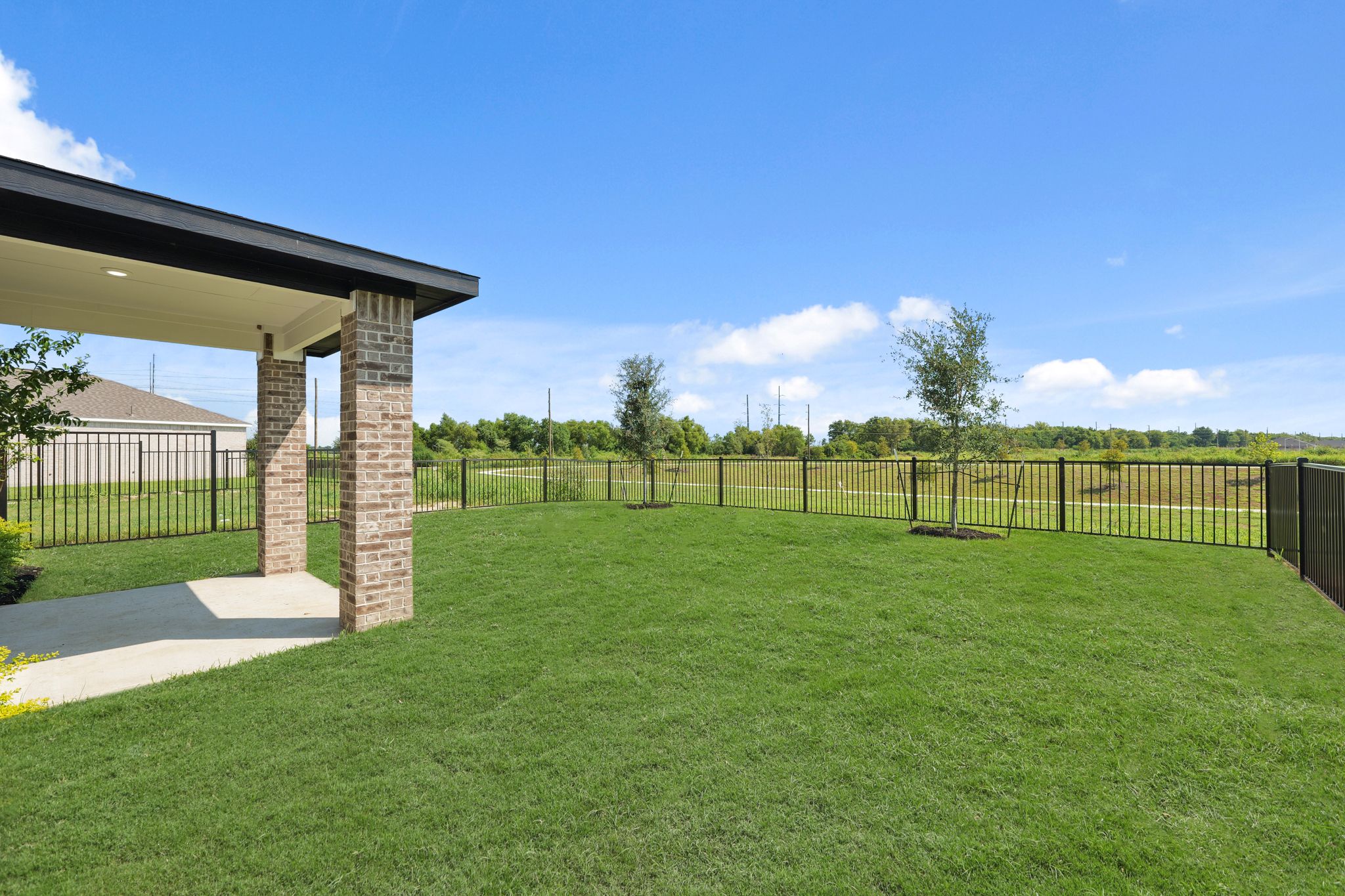A fenced in yard with a brick structure and a building in the background.